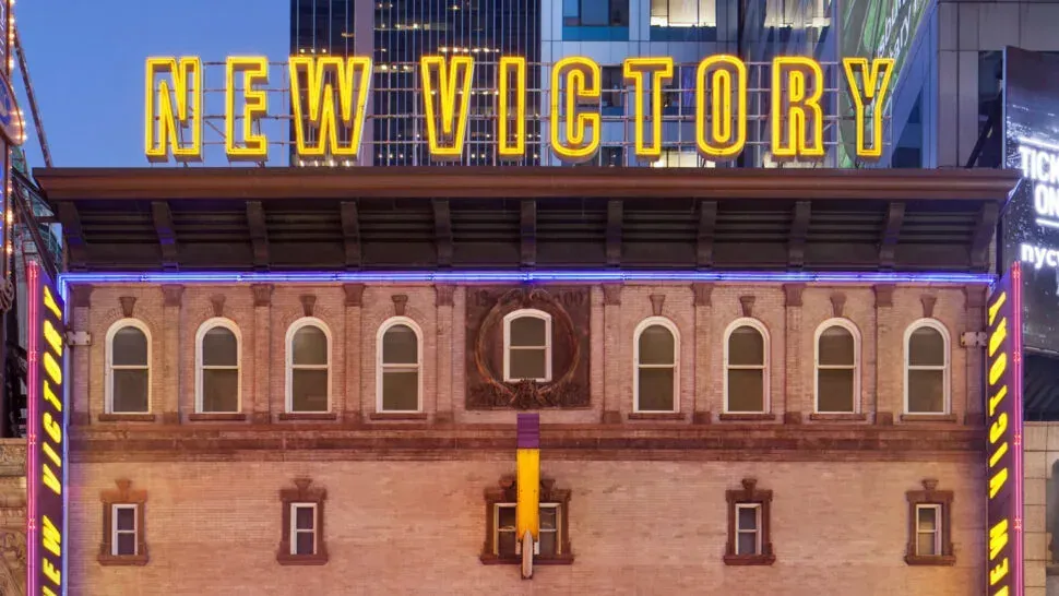 New Victory Theater facade on 42nd Street with the marquee lit in yellow.